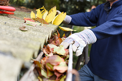 Gutter cleaning in Old Bridge, gutter clogged with leaves shown being cleaned out by a gloved hand